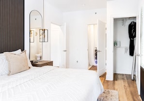 Un dormitorio con cama, mesita de noche, espejo y armario.