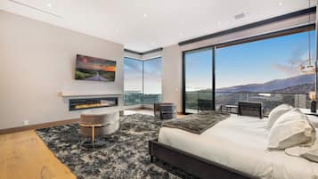 Une chambre moderne dotée d’un grand lit, d’une cheminée, d’un coin repas et d’un balcon offrant une vue sur les montagnes.