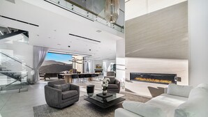 A spacious living area with a fireplace, modern furniture, and a view of the outdoors. - Linda Flora Modern Estate (Los Angeles)