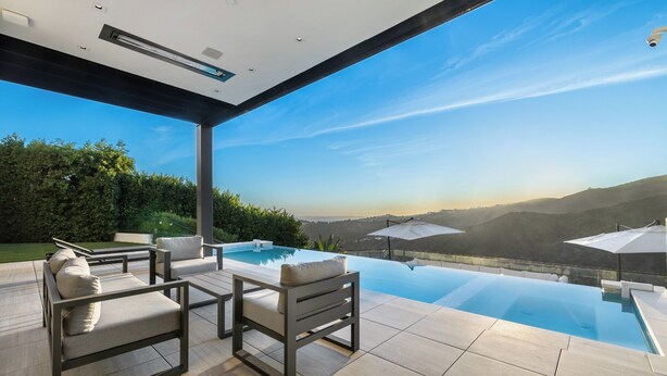 An infinity pool with a clear view of the surrounding landscape, outdoor seating area, and a modern architectural design. - Linda Flora Modern Estate (Los Angeles)