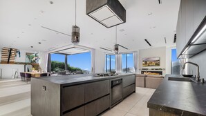 A modern kitchen with a large island, built-in appliances, and a view of the outdoors. - Linda Flora Modern Estate (Los Angeles)