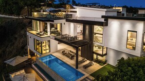 A modern house with a large swimming pool, outdoor seating, and a well-lit patio area. - Linda Flora Modern Estate (Los Angeles)