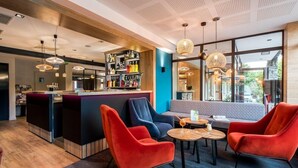 A modern bar area with a bar counter, seating, and a view through large windows.