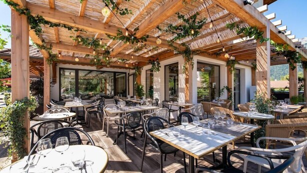 An outdoor patio with wooden pergolas, tables, and chairs.
