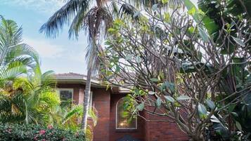 A brick building with a number '526' above the entrance, surrounded by lush greenery and a palm tree.