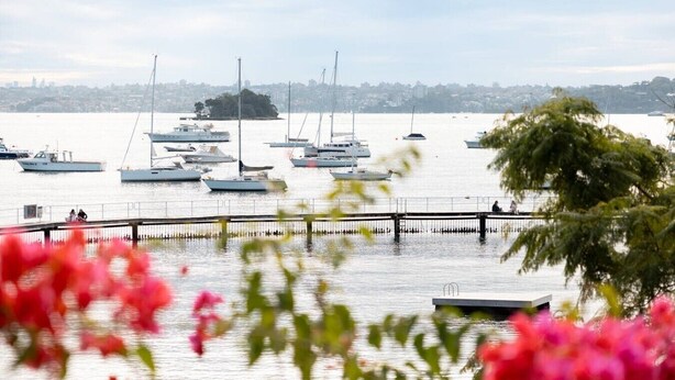A marina with boats docked, a pier, and a distant cityscape. - Double Bay Art Deco Apartment with Harbour Vistas (Double Bay)