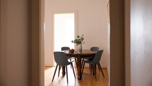 A dining area with a round table, four chairs, a vase with a plant, and a door leading to another room. - Double Bay Art Deco Apartment with Harbour Vistas (Double Bay)