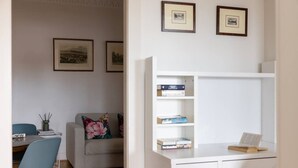 A room with a desk, bookshelves, a sofa, and framed pictures on the wall. - Double Bay Art Deco Apartment with Harbour Vistas (Double Bay)