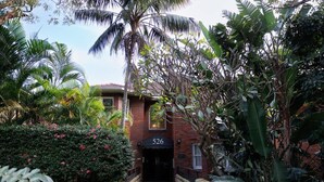 A brick building with a number '526' sign, surrounded by lush tropical vegetation. - Double Bay Art Deco Apartment with Harbour Vistas (Double Bay)