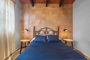 A bedroom with a bed, two nightstands, a curtain, and a tiled wall.