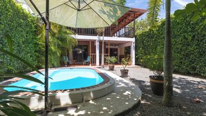 A swimming pool with a surrounding deck, a covered patio area, and a view of a two-story building with balconies. - Casa Toucan,with a privat pool and a short walk from Bahia Ballena NP (Uvita)