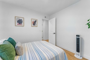 Ein Schlafzimmer mit einem Bett, Kissen, einem Standheizkörper und zwei gerahmten Bildern an der Wand.