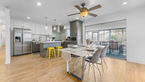 Una cocina moderna con una isla central, electrodomésticos de acero inoxidable y un comedor con mesa y sillas.