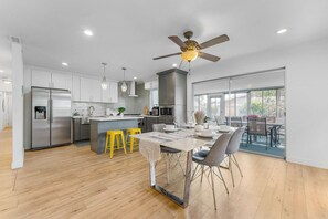 A modern kitchen with a central island, stainless steel appliances, and a dining area with a table and chairs.