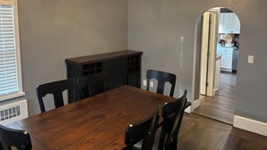 A dining room with a wooden table and chairs, a built-in cabinet, and a chandelier.