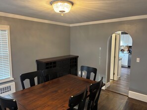 A dining room with a wooden table and chairs, a built-in cabinet, and a chandelier.
