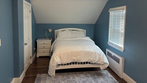 A bedroom with a bed, nightstand, lamp, and a window with blinds.