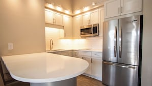 Una cocina moderna con un refrigerador de acero inoxidable, un microondas y armarios blancos.