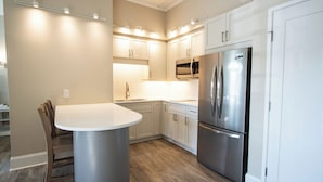 A modern kitchen with white cabinets, a stainless steel refrigerator, and a round dining table.