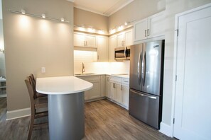 Una cocina moderna con armarios blancos, un refrigerador de acero inoxidable y una mesa de comedor redonda.