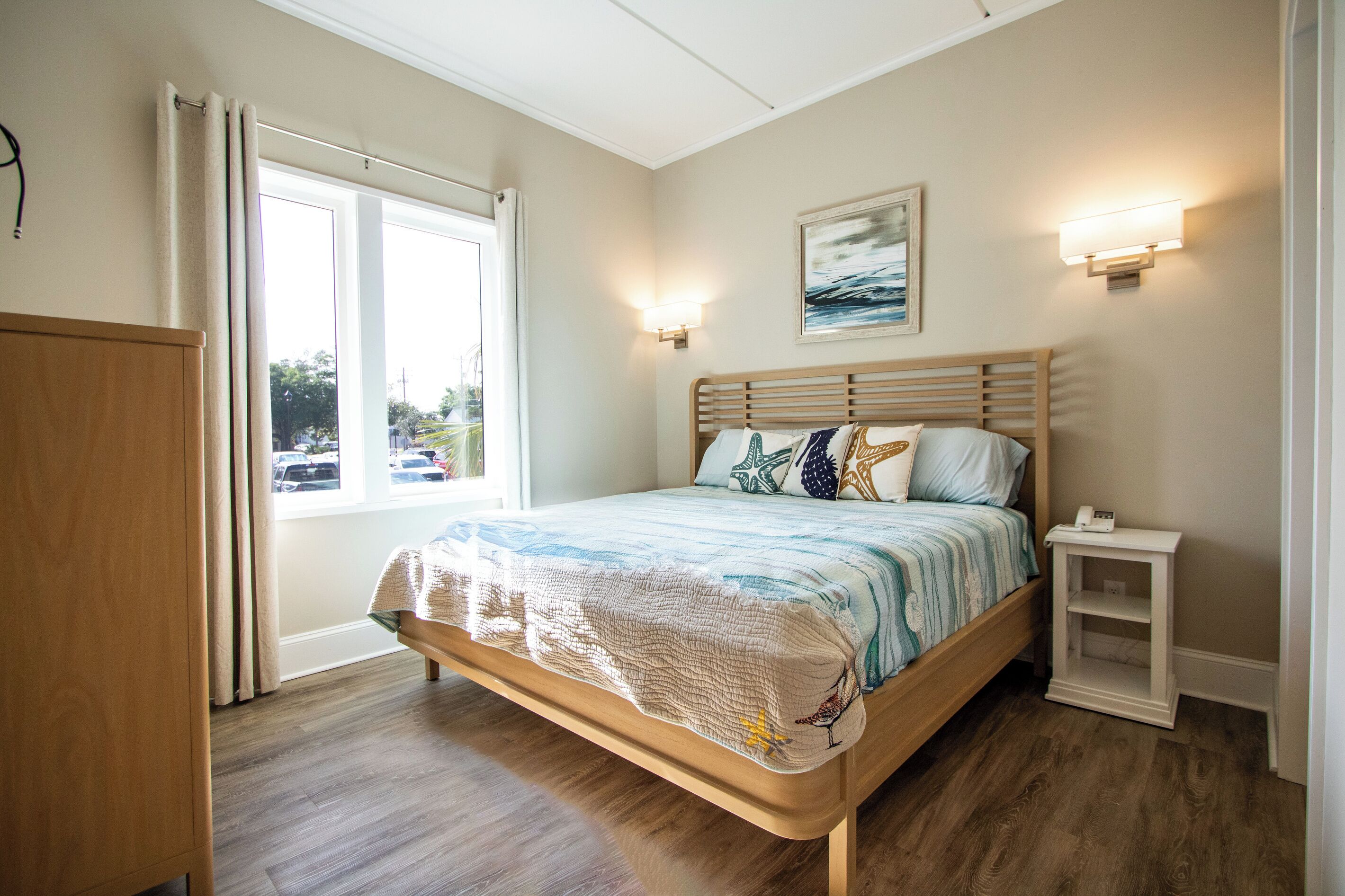 A bedroom with a bed, bedside table, and a window with curtains.
