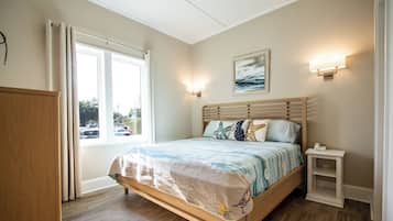 A bedroom with a bed, bedside table, and a window with curtains.