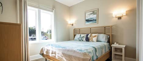 A bedroom with a bed, bedside table, and a window with curtains.