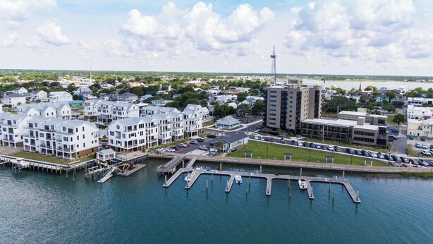 Un puerto deportivo con barcos amarrados, una zona de estacionamiento y edificios residenciales con balcones.