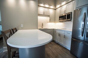 Een moderne keuken met een centraal eiland, roestvrijstalen apparatuur en witte kastjes.