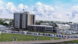 A multi-story building with a prominent 'bask' sign, surrounded by a parking lot and a body of water.