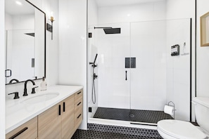 A modern bathroom with a glass-enclosed shower, a white sink, and a toilet.