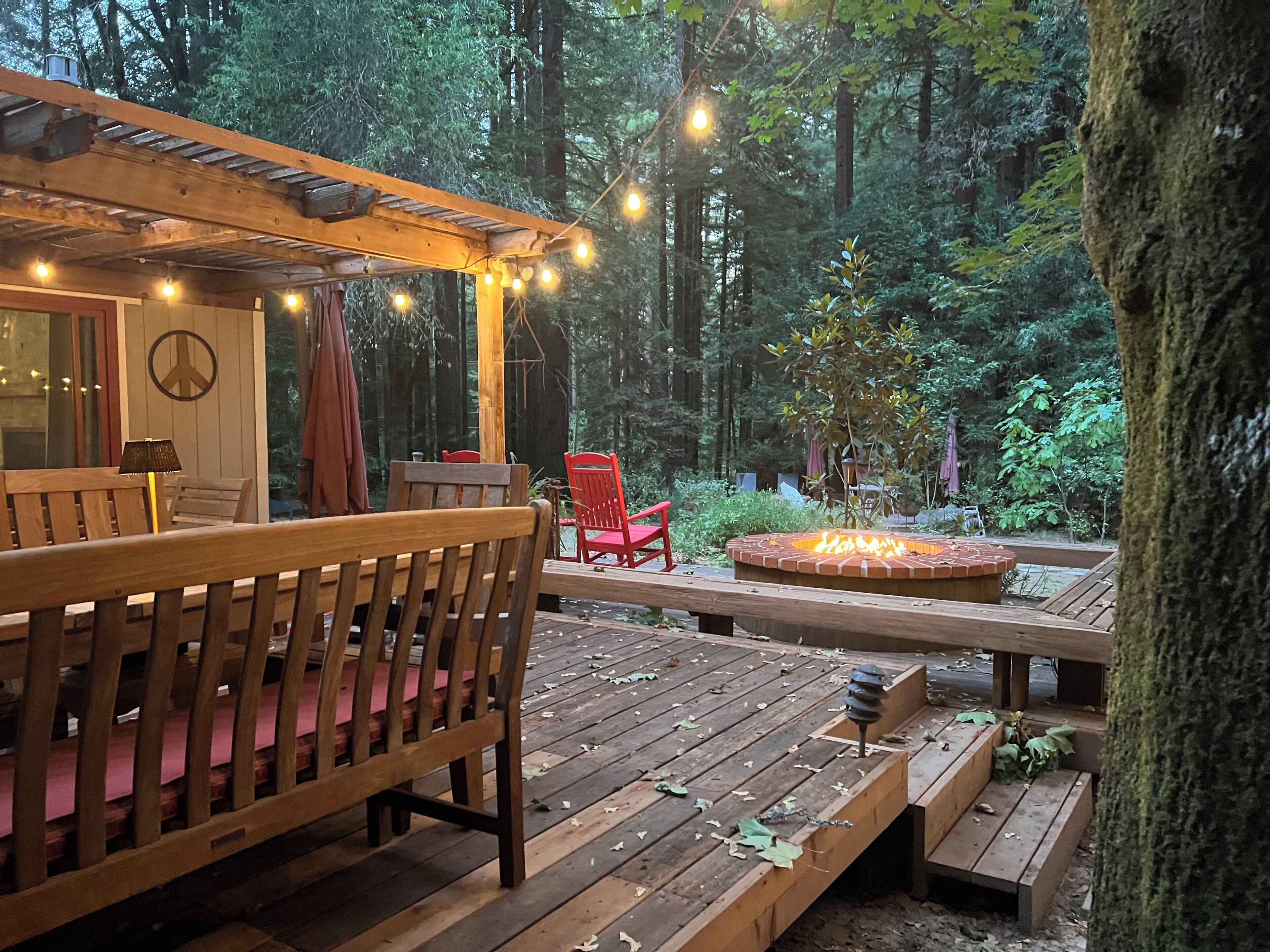 Une terrasse en bois avec un foyer, des sièges d’extérieur et des guirlandes lumineuses.