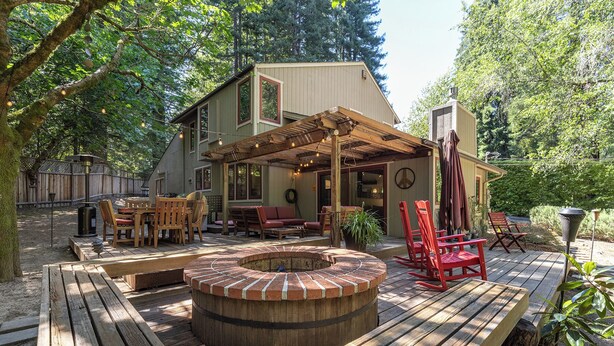 Um deck de madeira com hidromassagem, móveis para área externa e um pérgola.