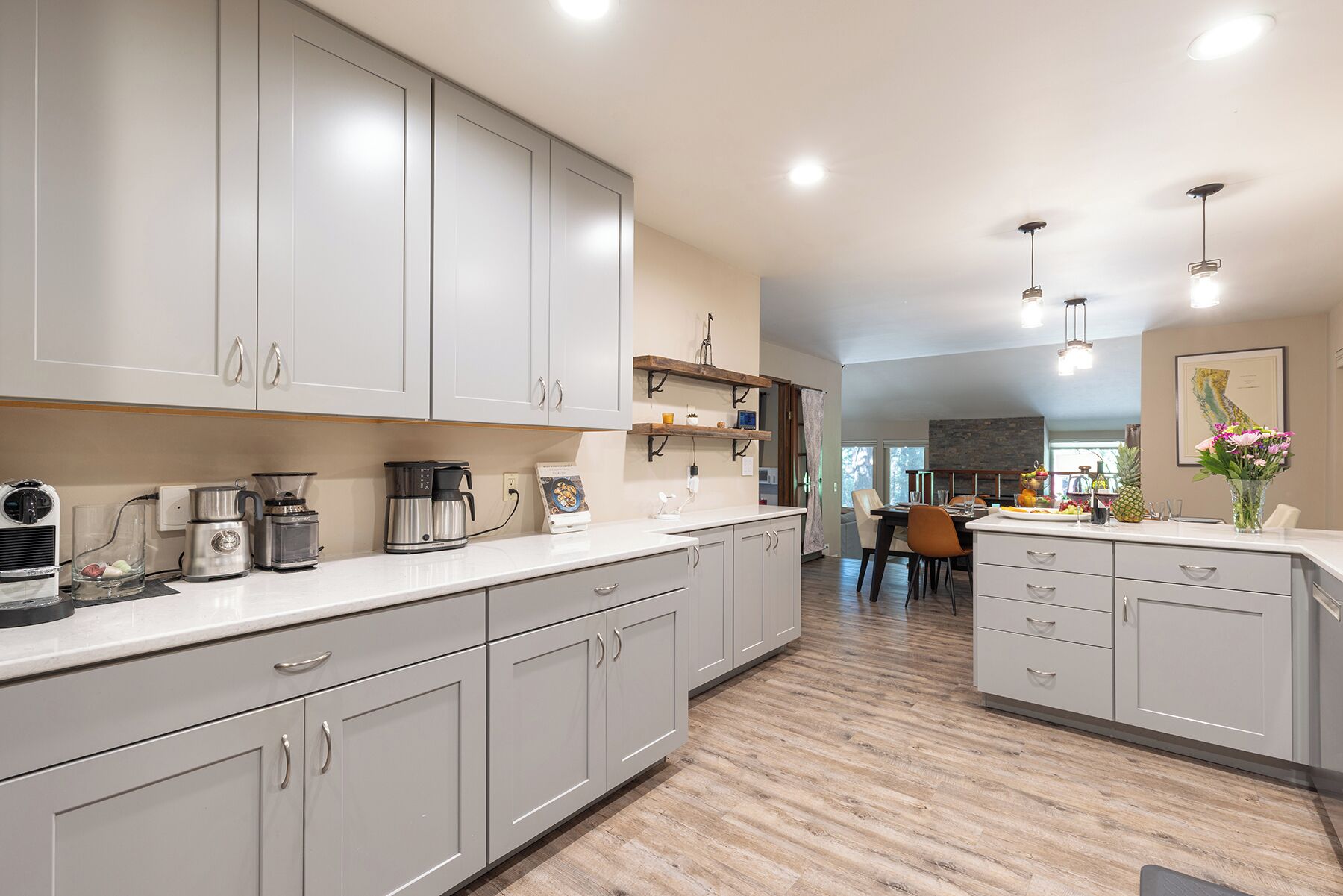 Una cocina moderna con armarios grises, electrodomésticos de acero inoxidable y una zona de comedor de madera.