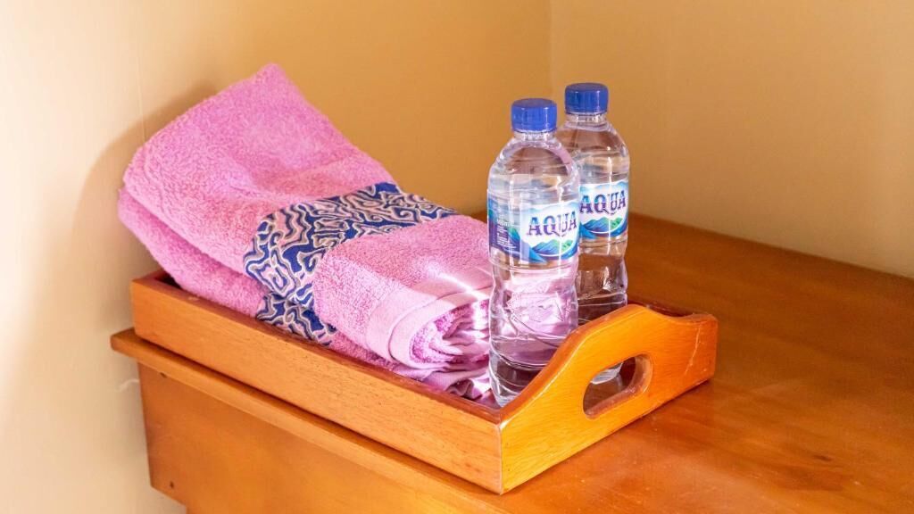 A wooden chest with a pink towel and two bottles of water.