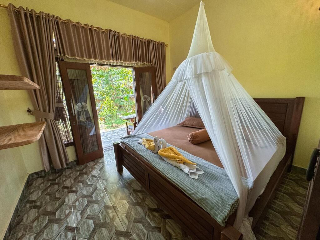A bed with a canopy, a wooden bench, a door with curtains, and a patterned floor.
