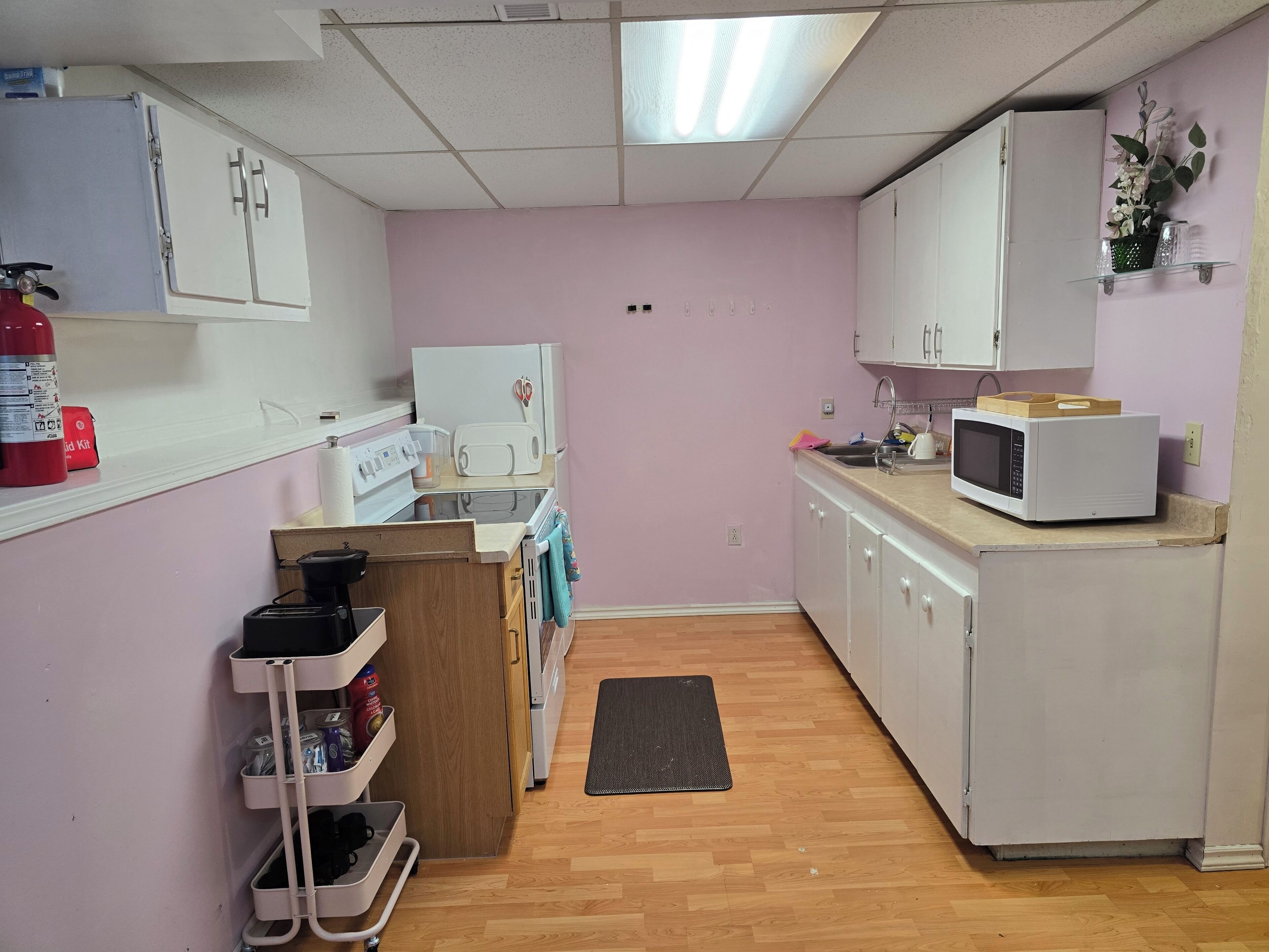 A compact kitchen with white cabinets, a microwave, a toaster, and a small sink.