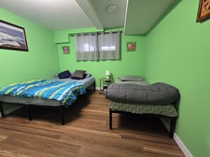 Une chambre avec deux lits, une table de chevet, une lampe et une fenêtre avec des rideaux.