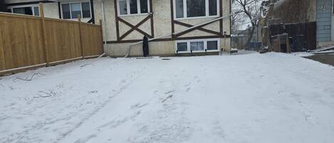 A house with a wooden fence, a garage, and a snow-covered yard.