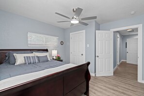 Ein Schlafzimmer mit einem Bett, Deckenventilator und zwei Türen zu anderen Räumen.