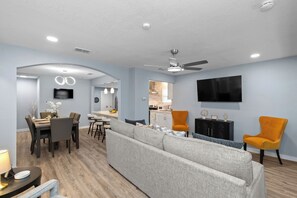 Ein modernes Wohnzimmer mit Ecksofa, Essbereich, Küche und Deckenventilator.