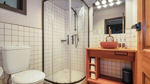 Une salle de bain moderne avec une douche à parois de verre, des toilettes blanches et un meuble-lavabo en bois doté d’un grand évier.