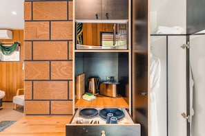 Eine kompakte Küchenzeile mit Mikrowelle, Toaster und Wasserkocher, einer Holzwandverkleidung und einer kleinen Essecke.