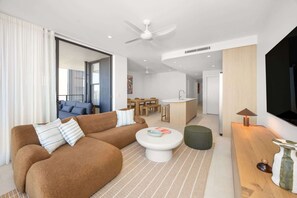 Ein modernes Wohnzimmer mit einem braunen Sofa, einem weißen Couchtisch und einem Fernseher an der Wand.