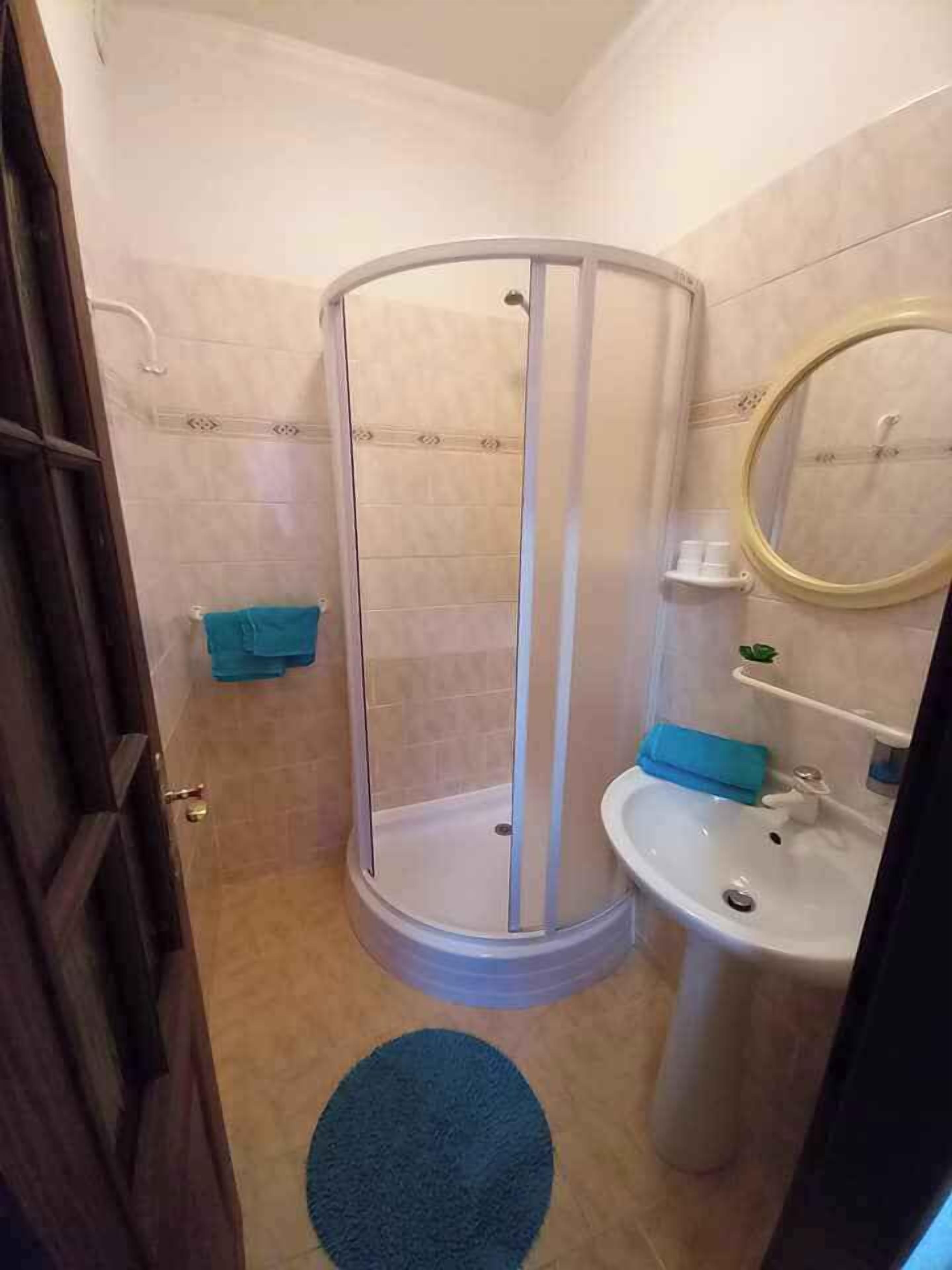 Ein Badezimmer mit Duschkabine, Waschbecken und Spiegel.