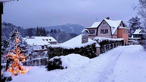 Un barrio residencial cubierto de nieve, con casas, un árbol nevado y un cielo despejado.