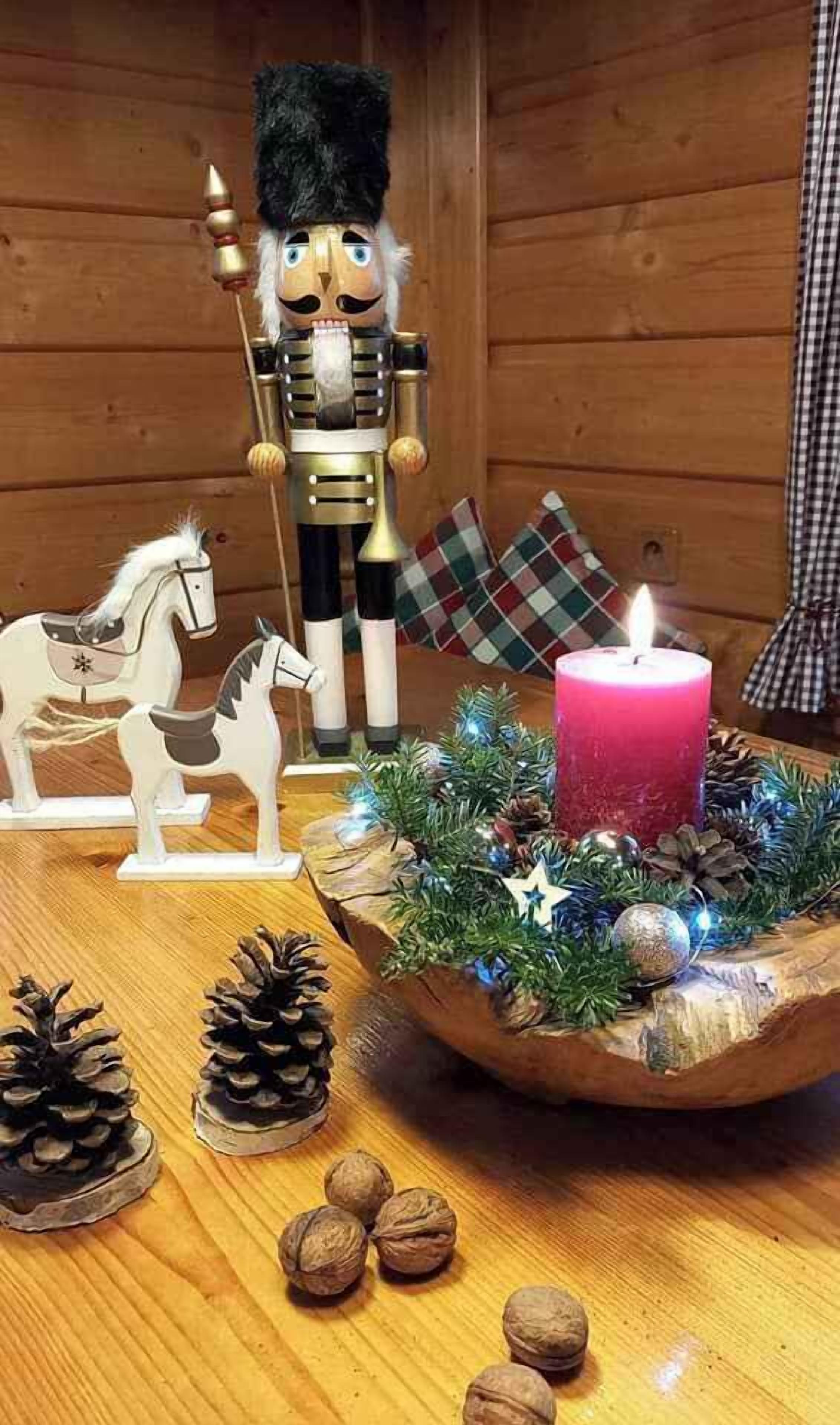 A wooden table with a nutcracker, a candle, and horse-shaped decorations.