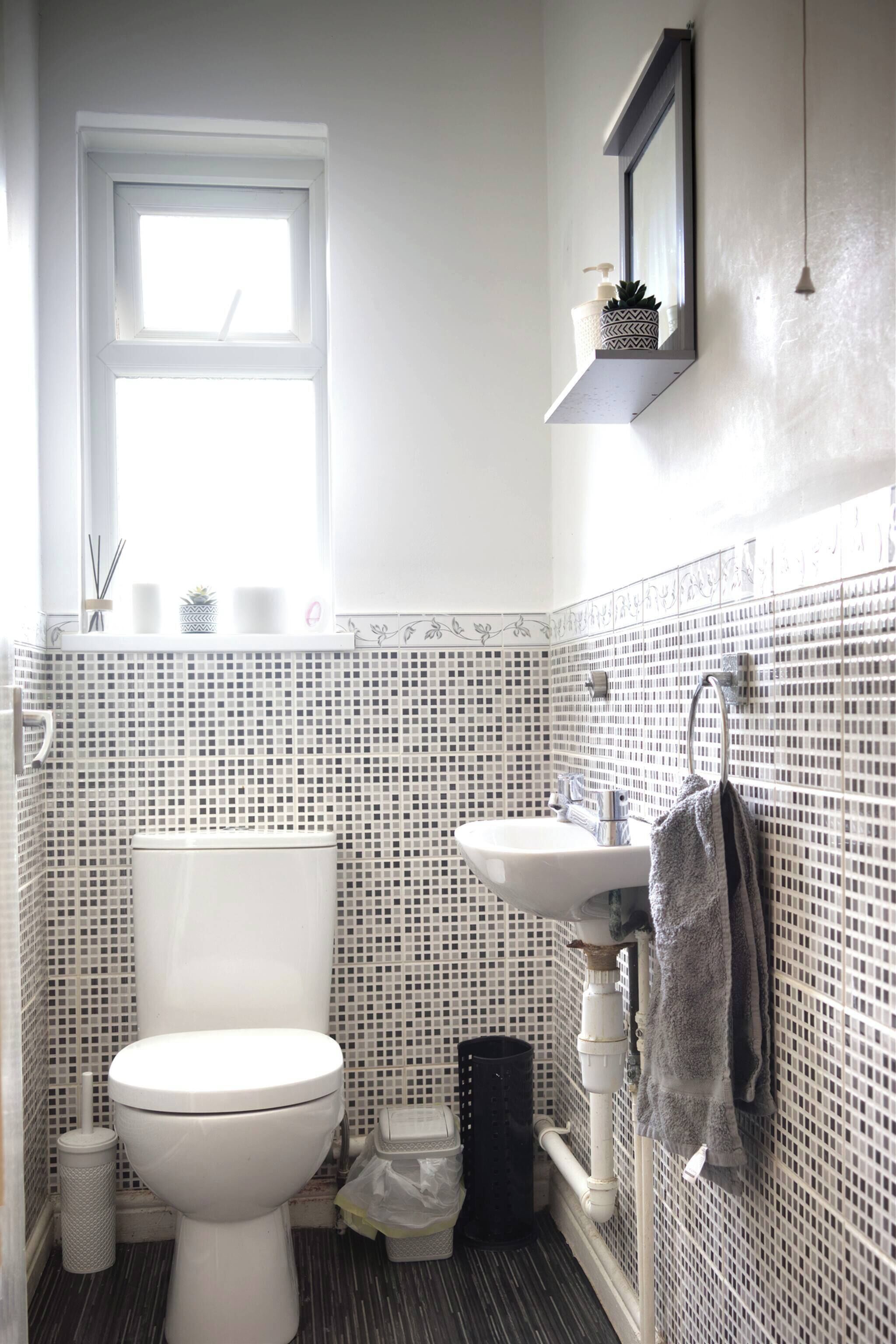 A bathroom with a toilet, sink, and a window.