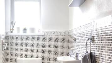 A bathroom with a toilet, sink, and a window.