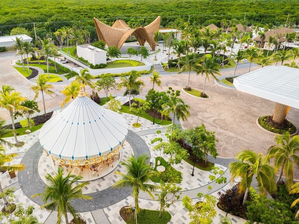 Un resort con una plaza circular central, palmeras y arquitectura moderna.